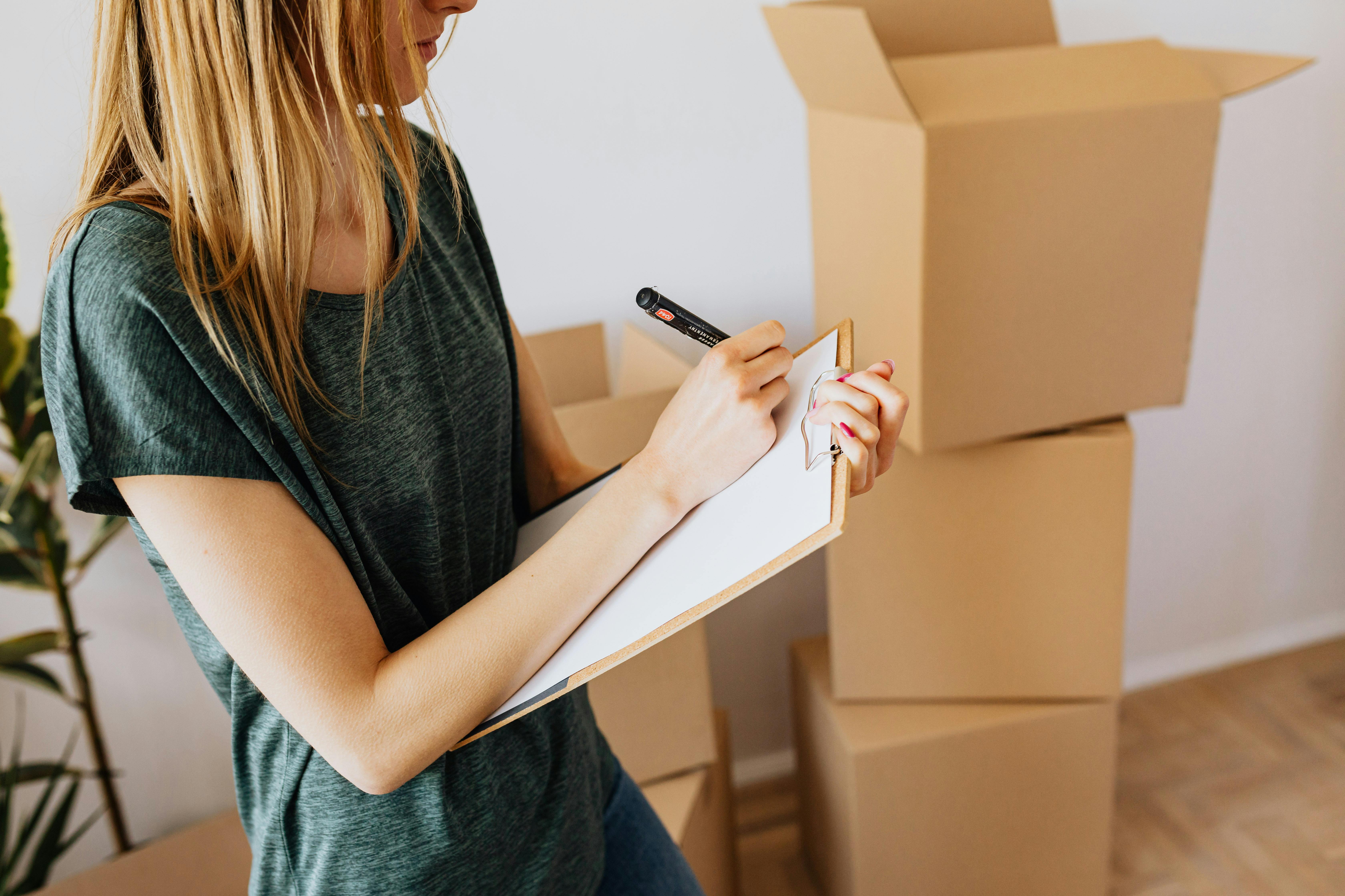Woman creating a moving checklist with boxes in background